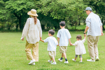 夏休みに公園を手を繋いで歩く家族・ファミリーの後ろ姿（レジャー・アウトドア・思い出・コピースペース）

