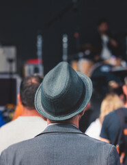 Crowded open air festival concert with scene lights with musicians band on stage at the venue, rock show performance, with concert-goers attendees, audience on dance floor during summer festival