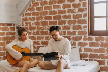 Asian couple lover concentrate on create a song with guitar and tablet.