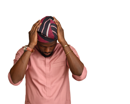 Portrait of Happy Handsome black Man holding his head as he adjusts his African cap in Cozy studio at Home Standing on the brown backdrop. Close-up Profile Shot.