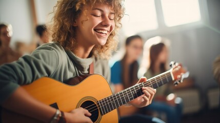 A smiling teenager strumming an acoustic guitar in a sunlit room - obrazy, fototapety, plakaty