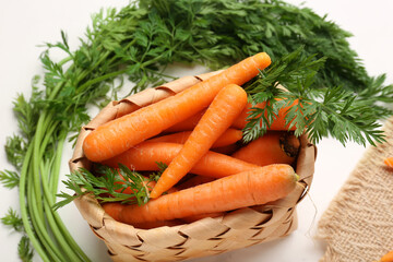 Wicker basket with fresh carrots on white background