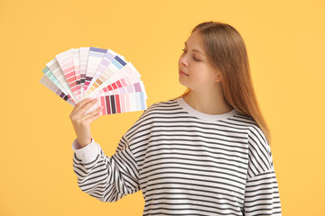 Young woman with many color samples on yellow background