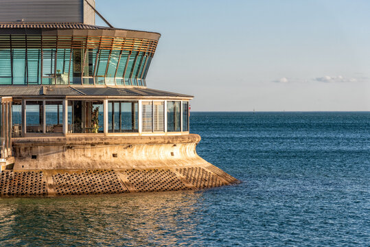 A rounded building with large glass windows extends out into Port Phillip Bay
