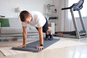 Sporty young man doing push-ups at home