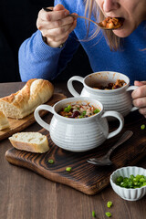 Unrecognizable woman taking a spoonful from a bowl full of chili con carne.