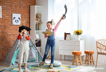 Cute little children playing with adventure book at home - obrazy, fototapety, plakaty