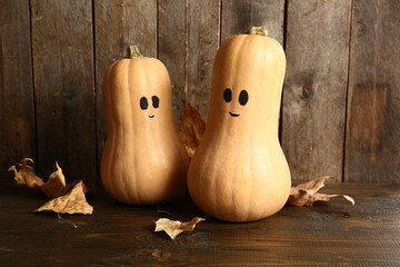 Cute Halloween pumpkins with drawn faces on wooden background