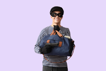 Male thief with gun and bag of money on lilac background
