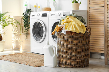 Wicker basket with dirty clothes and detergent in laundry room