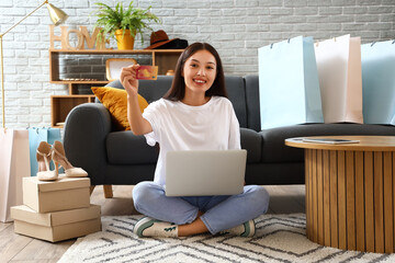 Young Asian woman with credit card and laptop shopping online at home