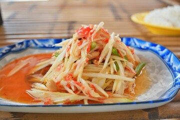 The Traditional Thai food papaya salad prepared with fine slices of papaya, tomatoes, green beans and peanuts.