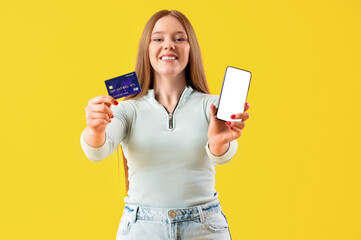 Naklejka premium Young woman with credit card and mobile phone on yellow background