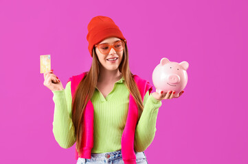 Young woman with credit card and piggy bank on purple background