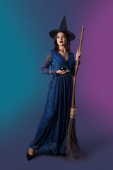 Young witch with crystal ball and broom on dark color background