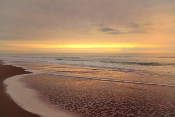 Fototapeta na wymiar Golden sunset on the beach, and cloudy sky. Beautiful seascape, copy space