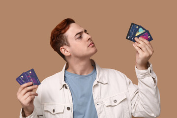 Young man with credit cards on brown background