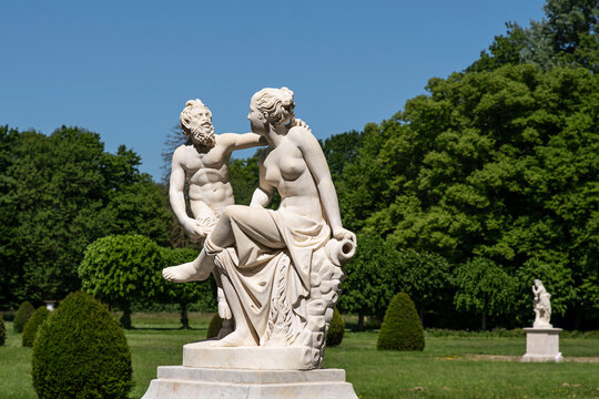 Statue of a couple, a woman and the devil, in a park with lots of vegetation in the Chaalis estate in France