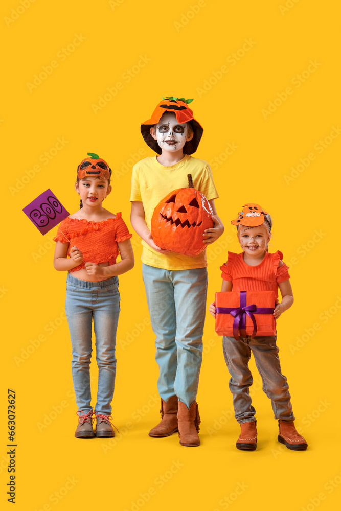 Sticker Little children dressed for Halloween with gift and pumpkin on yellow background