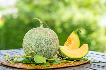 Cantaloupe melon with leaves in blur background. Sweet Orange Melon with leaf on green bokeh background.