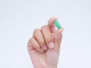 Hand holding green medical pills on white background