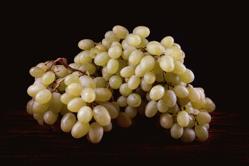 A bunch of green grapes on a dark background.