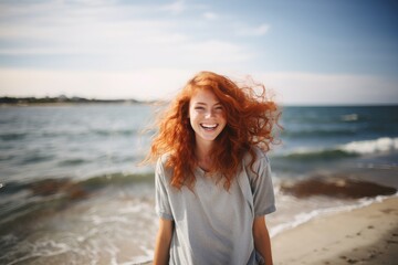 Happy redhead woman with tousled hair by lake