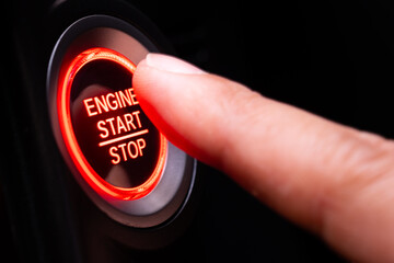 The driver's hand is pressing the car start button. Concept of transportation and technology