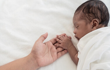 African black parent hands holding newborn baby fingers, Closeup mother’s hand holding their new...