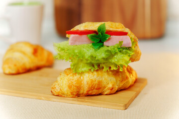 Croissant with ham ricotta, mint and salad close-up. Delicious breakfast