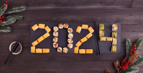 Selbstklebende Fototapeten 2024 Happy new year greeting banner. Assorted set of various sushi rolls with tuna, salmon, eel, avocado, vegetables. The sushi rolls are laid out in numbers 2024.  © Viktoriya