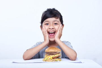 Smiling Little girl with a big cheeseburger with tomato, lettuce, arugula, beef and sauce