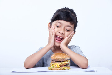 Smiling Little girl with a big cheeseburger with tomato, lettuce, arugula, beef and sauce