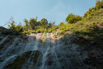 Fototapeta na wymiar Play of Light: Tumpak Sewu Waterfall in Sun and Shadow