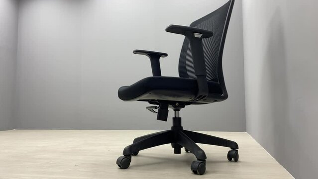 Black office chair sliding on floor indoor room with empty space.