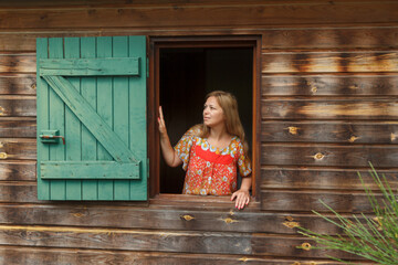 Woman in window of wooden house
