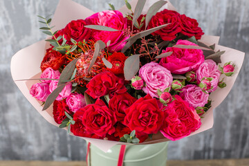 Red Beautiful bouquet of mixed flowers in woman hand. Floral shop concept . Beautiful fresh cut bouquet. Flowers delivery