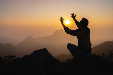 Silhouette of christian prayers raising hand while praying to the Jesus spirituality and...