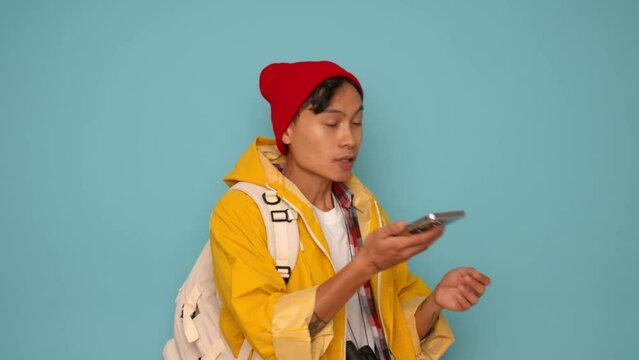 young asian tourist get lost man wearing a red cap and yellow t-shirt, holding a mobile phone trying to find a way