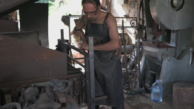 Front view of a blacksmith in his workshop marking a decorative grille with a scarp.