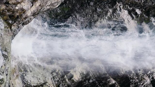 Waterfall of the Barskun gorge "Manas Bowl". A picturesque waterfall flows between dense spruce forests and rocks. Sun glare on the water. Splashes of water. Issyk-Kul region, Kyrgyzstan. 4K