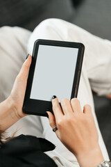 Young woman sitting the couch with an e-book
