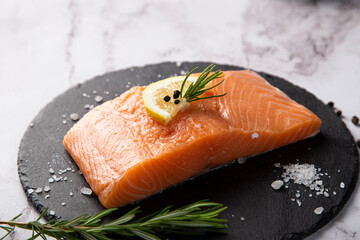 raw salmon served on a slate plate with lemon and rosemary on the table
