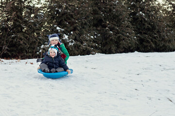Fototapeta na wymiar Brothers sledding together in the snow