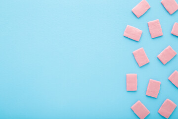 Pink sweet chewing gum pads on light blue table background. Pastel color. Closeup. Empty place for text. Top down view.