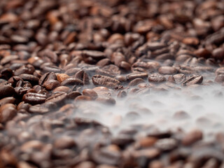 Close-up of roasted coffee beans with smoke. Coffee beans in smoke.