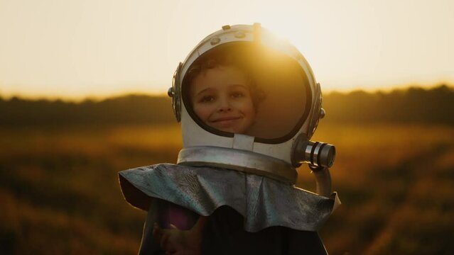 Little Boy Wants To Be An Astronaut, Portrait Of Smiling Child In Spaceman Helmet Walking In Field