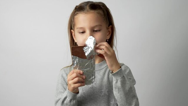 Child girl bites chocolate bar, white background, 4k