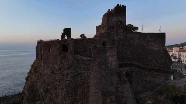 Il borgo marinaro di Aci Castello, Sicilia, Italia.
Vista aerea all'alba del castello sulla roccia vulcanica a picco sul mare.
