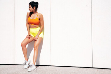 Fitness woman in sports clothing. Sexy young beautiful model athlete doing fitness workout. Female making exercises in the street at sunny day. Stretching out before training